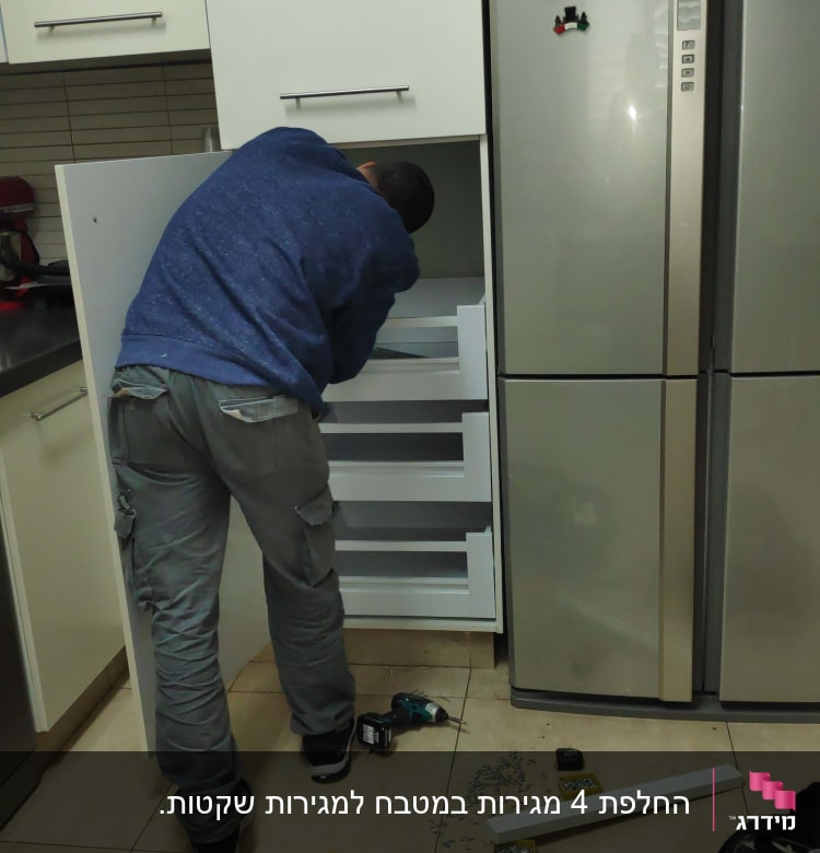 אדם מתקין מגירות במטבח עם כלי עבודה